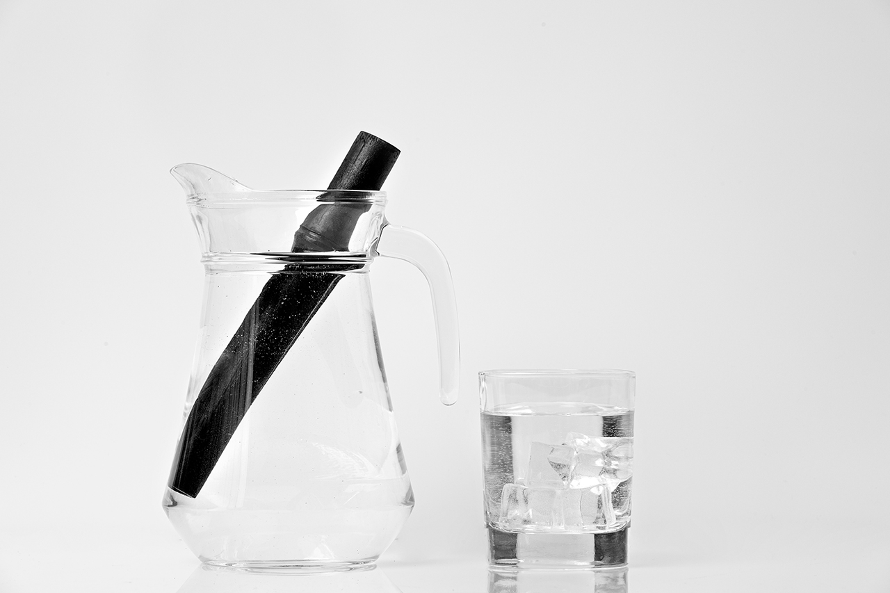 Bamboo charcoal water filter stick and glass of water. Natural bamboo charcoal is a powerful purifier which refreshes tap water